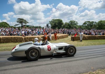 Sir Stirling Moss au volant de la Mercedes-Benz Silver Arrow W 196 R en 2015 au Goodwood Festival saluant le public et les commissaires.