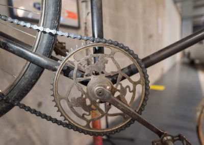 Pédalier d’un ancien vélo Peugeot avec la présence de trois lions et le nom Peugeot gravé.